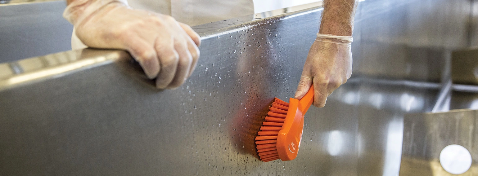Vikan short handle washing brush cleaning a steel surface